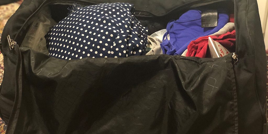 Reisetasche gepackt mit T-Shirts, Schal und anderer Kleidung