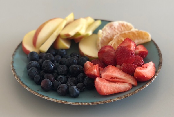 Ein bunter Obstteller mit Heidelbeeren, Erdbeeren,  Orangen und Äpfeln